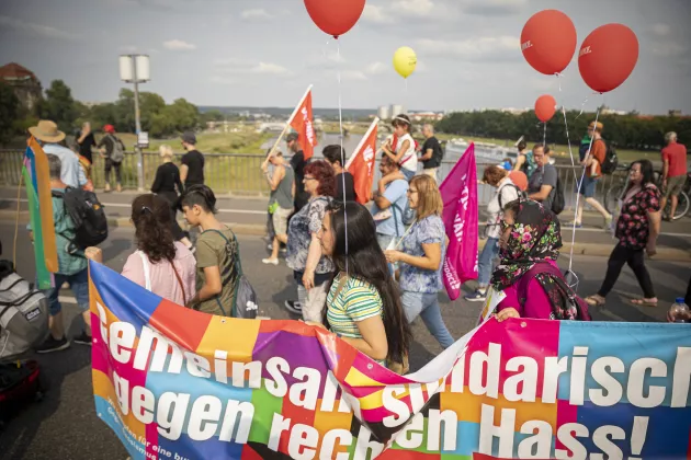 Menschen demonstrieren mit einem bunten Banner und Luftballons gegen Rassismnus