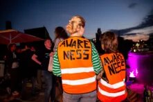 Zwei Personen mit Awareness-Warnwesten stehen mit dem Rücken zum Betrachter, vor einer Festivalkulisse
